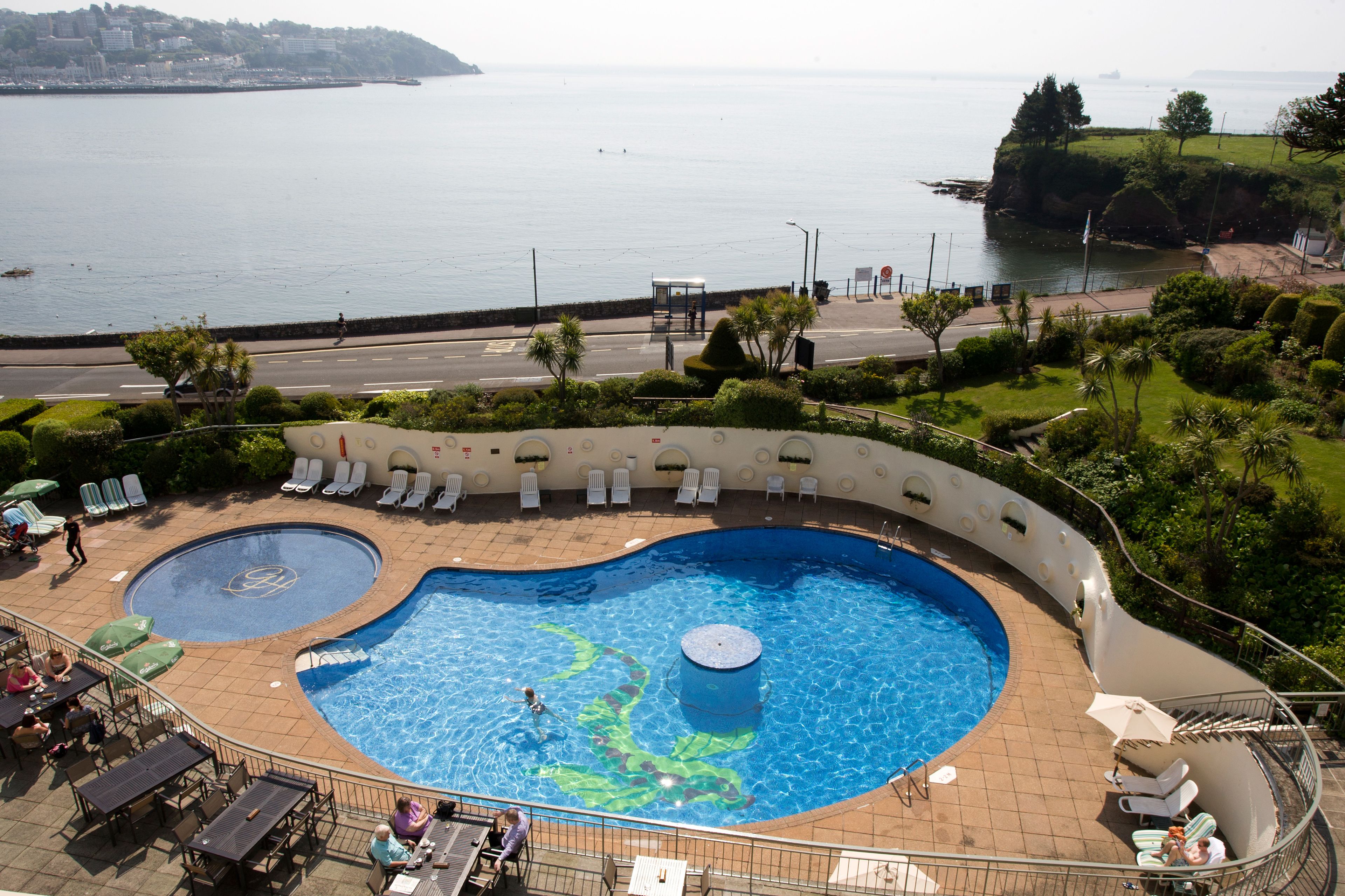 Une piscine avec des chaises longues et vue sur la mer.