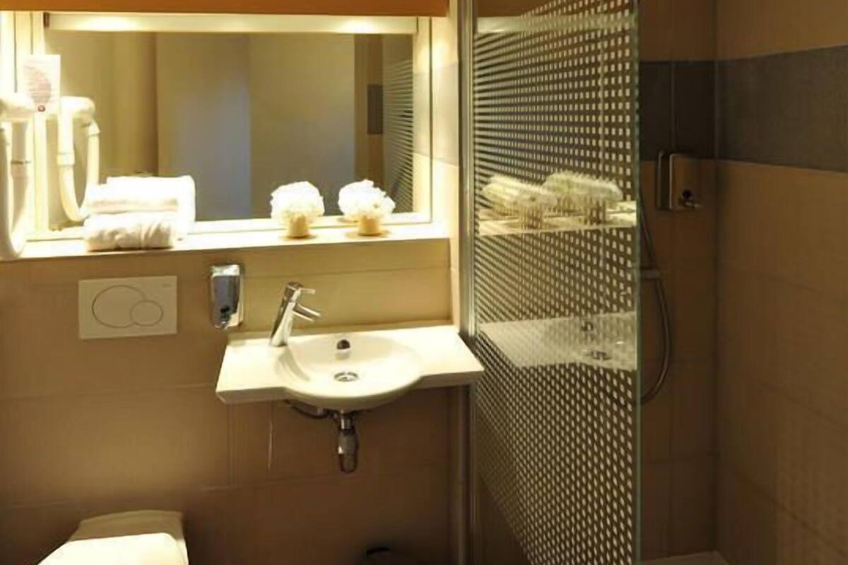 A compact bathroom with a toilet, sink, and shower.