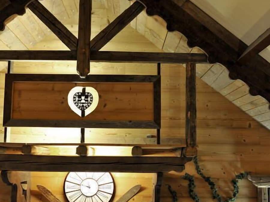 Interior de madera con un reloj, un letrero con forma de corazón y un plato decorativo.