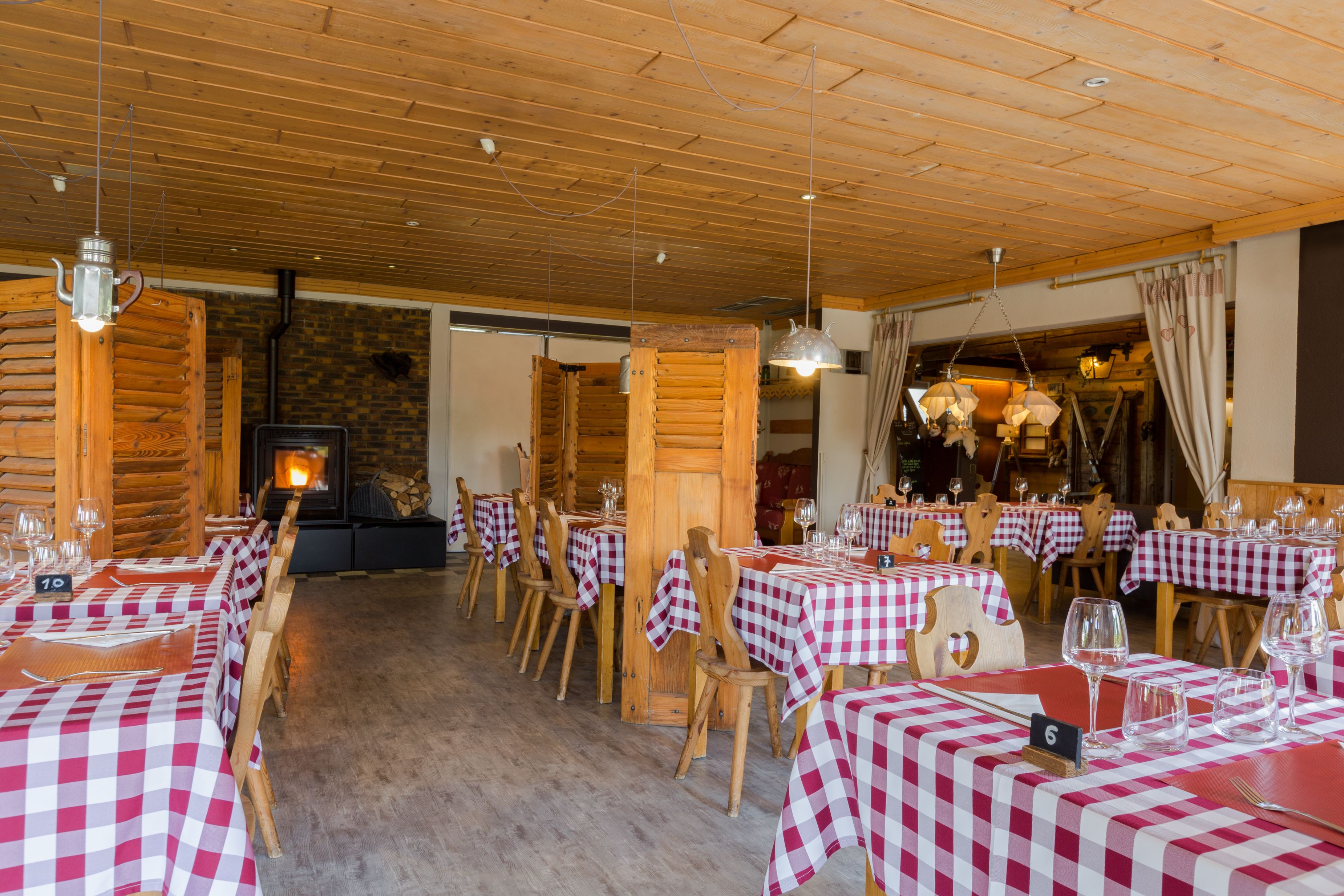 Ein Restaurant mit karierten Tischdecken, Holzkästen und hängenden Pendelleuchten.