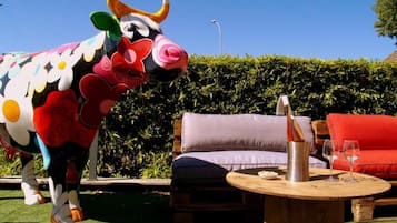Relax in a vibrant outdoor space with a colorful bull sculpture, comfortable seating, and a round table for socializing.