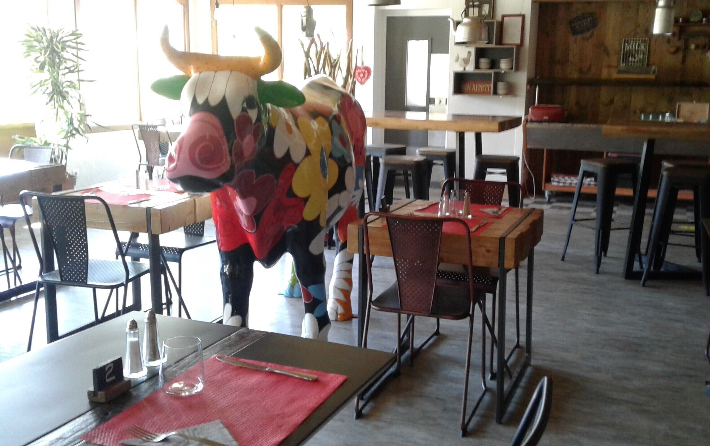 A dining area with tables and chairs, a bull statue, and a kitchen area in the background.