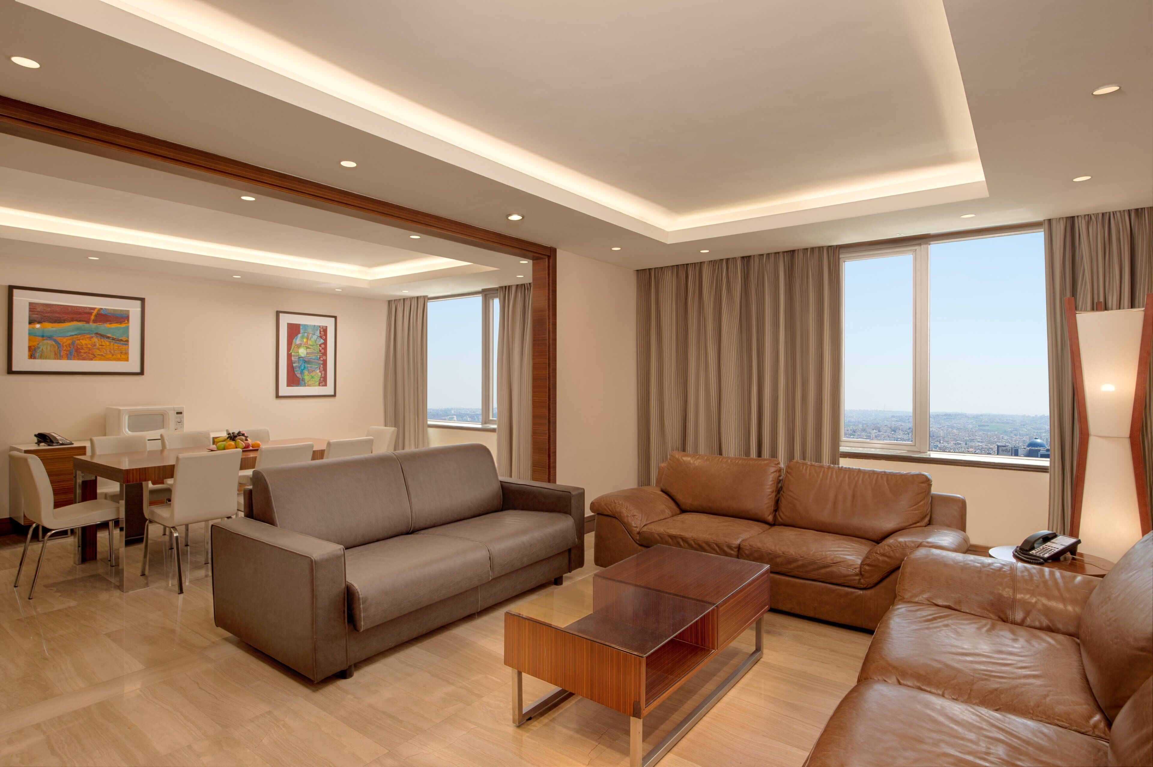 A modern living room with a sofa, a coffee table, and a dining area with a table and chairs.