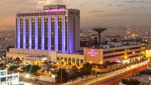 A large hotel with a prominent "Crowne Plaza" sign, multiple floors, and a view of the cityscape in the background. - Crowne Plaza Amman by IHG (Amman)