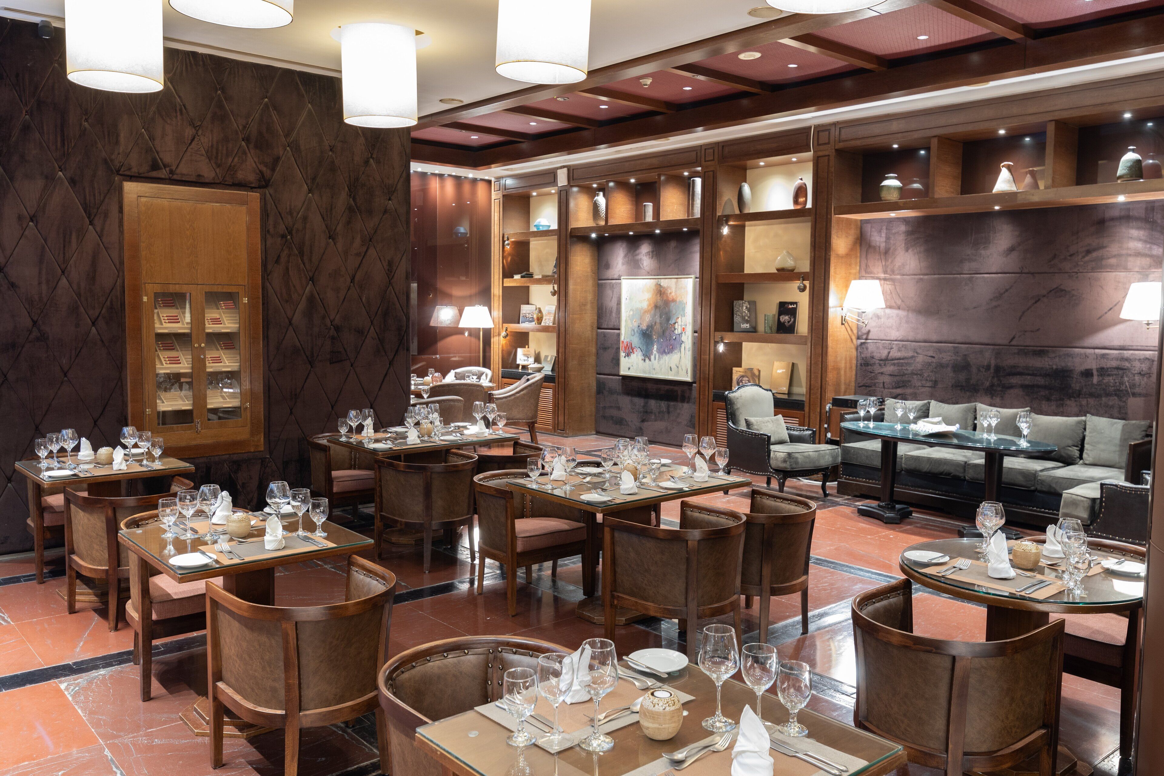 A restaurant with multiple dining tables and chairs, a wooden cabinet, and a sofa.