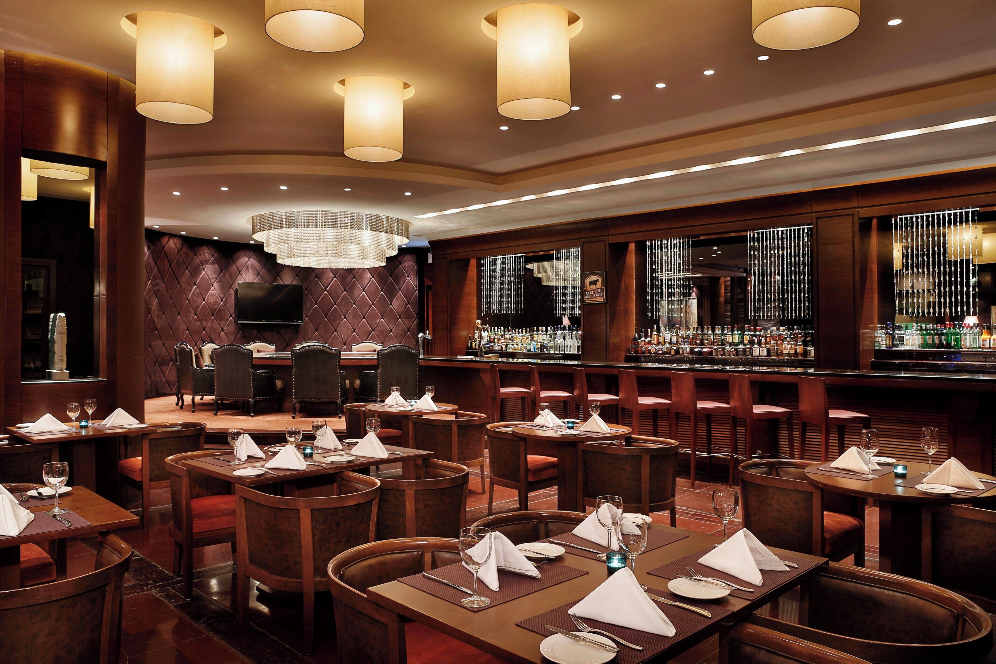 Un restaurant avec plusieurs tables, un bar et un lustre.
