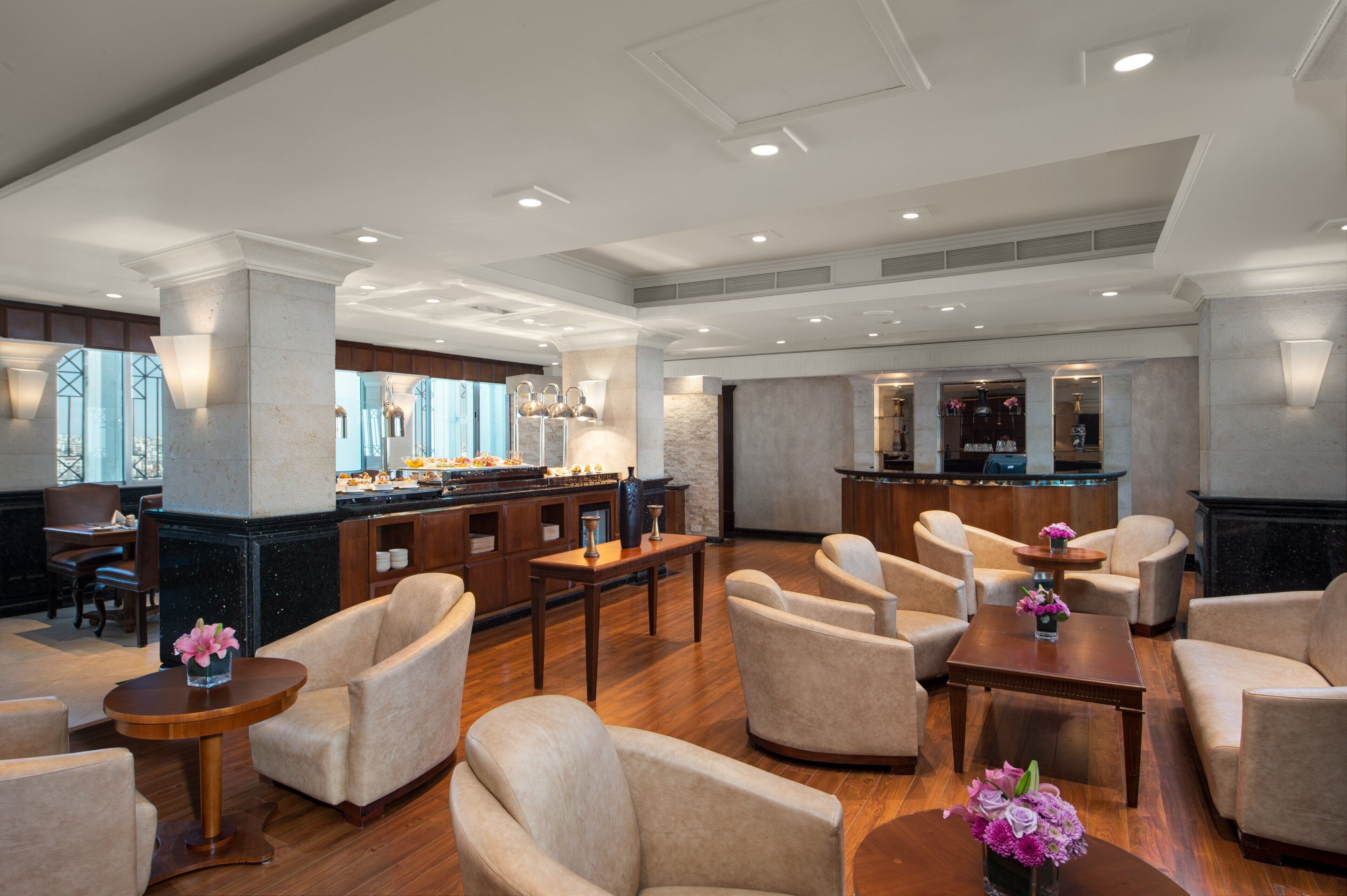 A spacious lobby with comfortable seating, a reception area, and a view of the city through large windows.