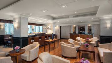 A spacious lobby with comfortable seating, a reception area, and a view of the city through large windows.