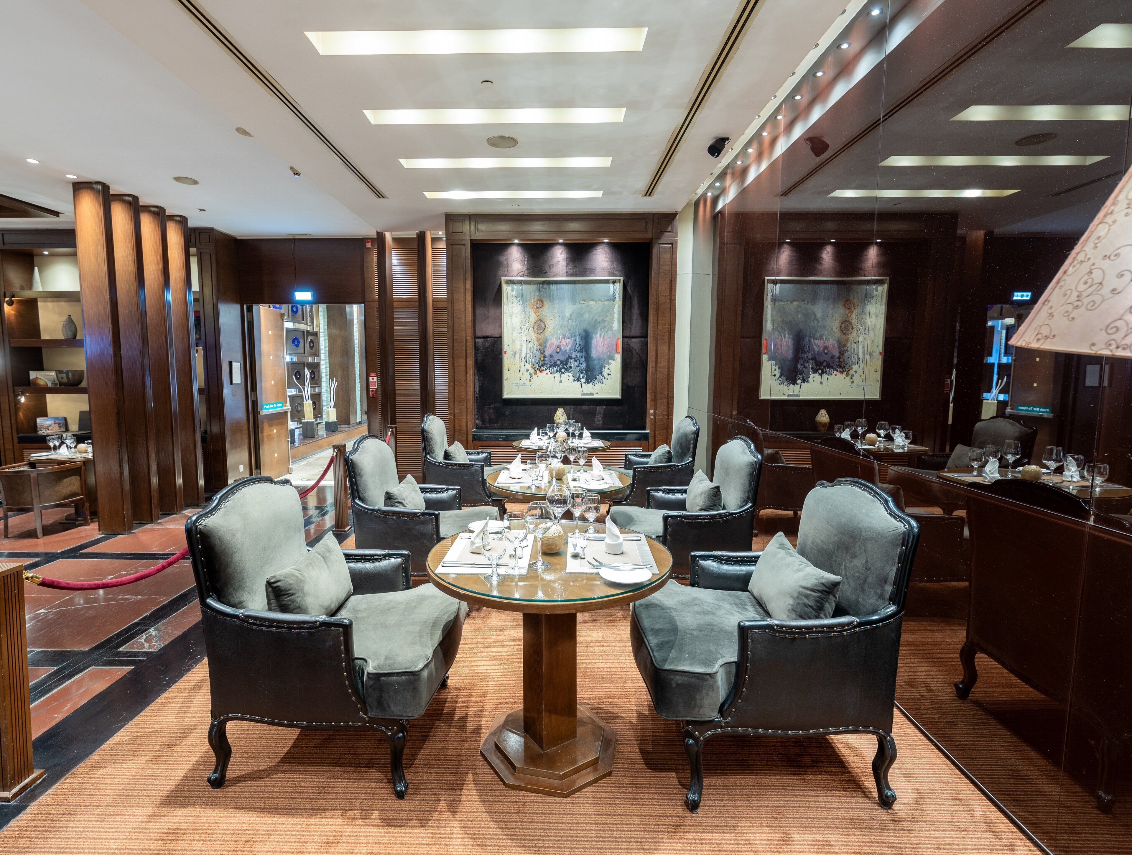 A dining area with round tables, leather chairs, and artwork on the walls.