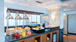 A buffet with various food items and beverages, wooden cabinets, and a marble countertop. - Crowne Plaza Amman by IHG (Amman)