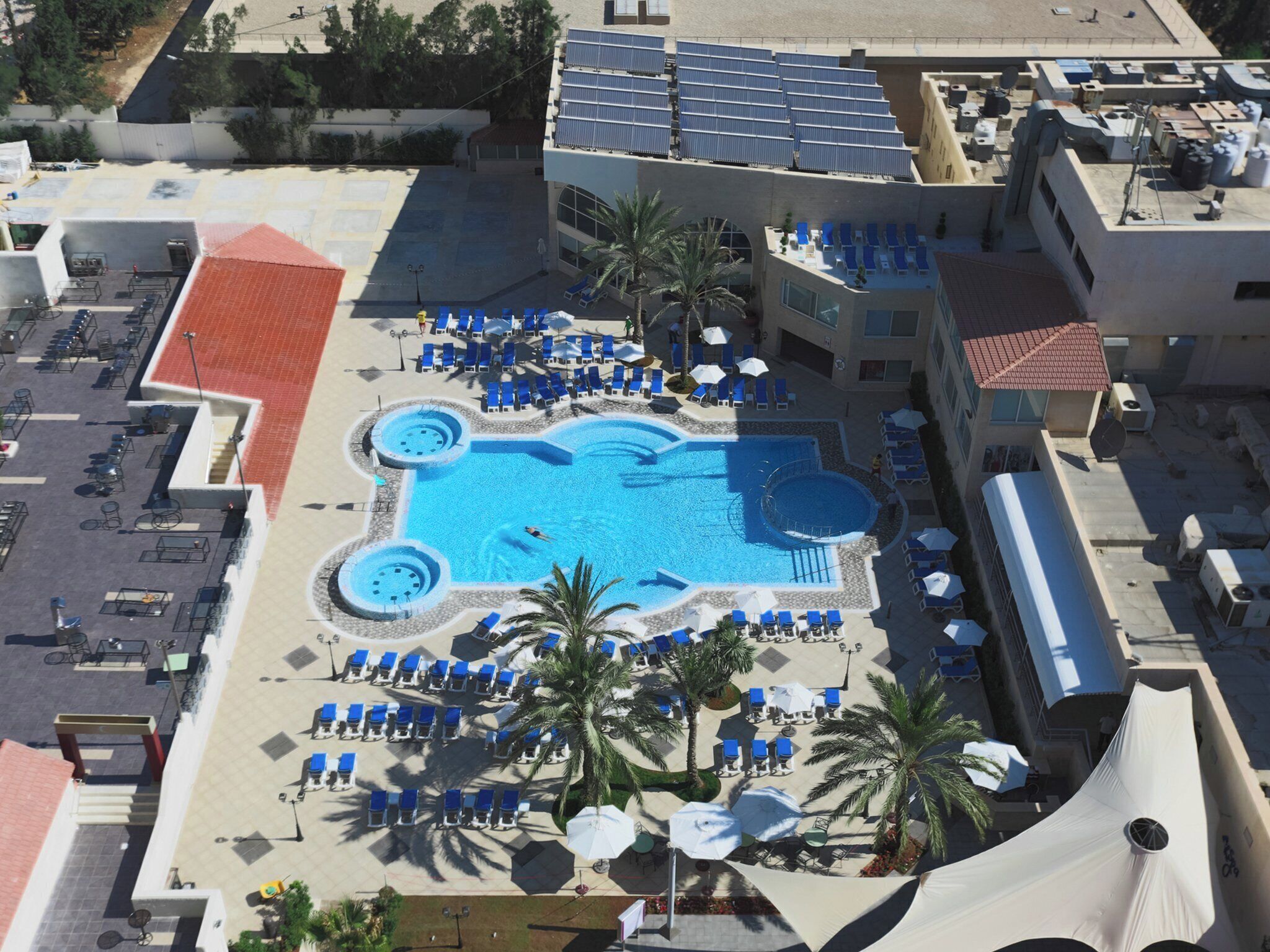 A rooftop pool area with multiple sun loungers and a central swimming pool.
