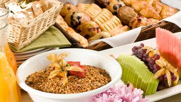 A breakfast buffet with various pastries, fruits, and a bowl of granola.