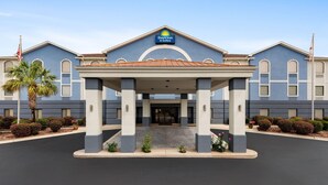 A Days Inn & Suites building with a covered entrance, American flags, and well-maintained landscaping. - Days Inn & Suites by Wyndham Prattville-Montgomery (Prattville)
