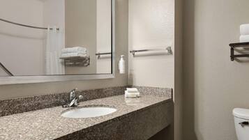 A bathroom with a granite countertop sink, a mirror, a towel rack, and a toilet.