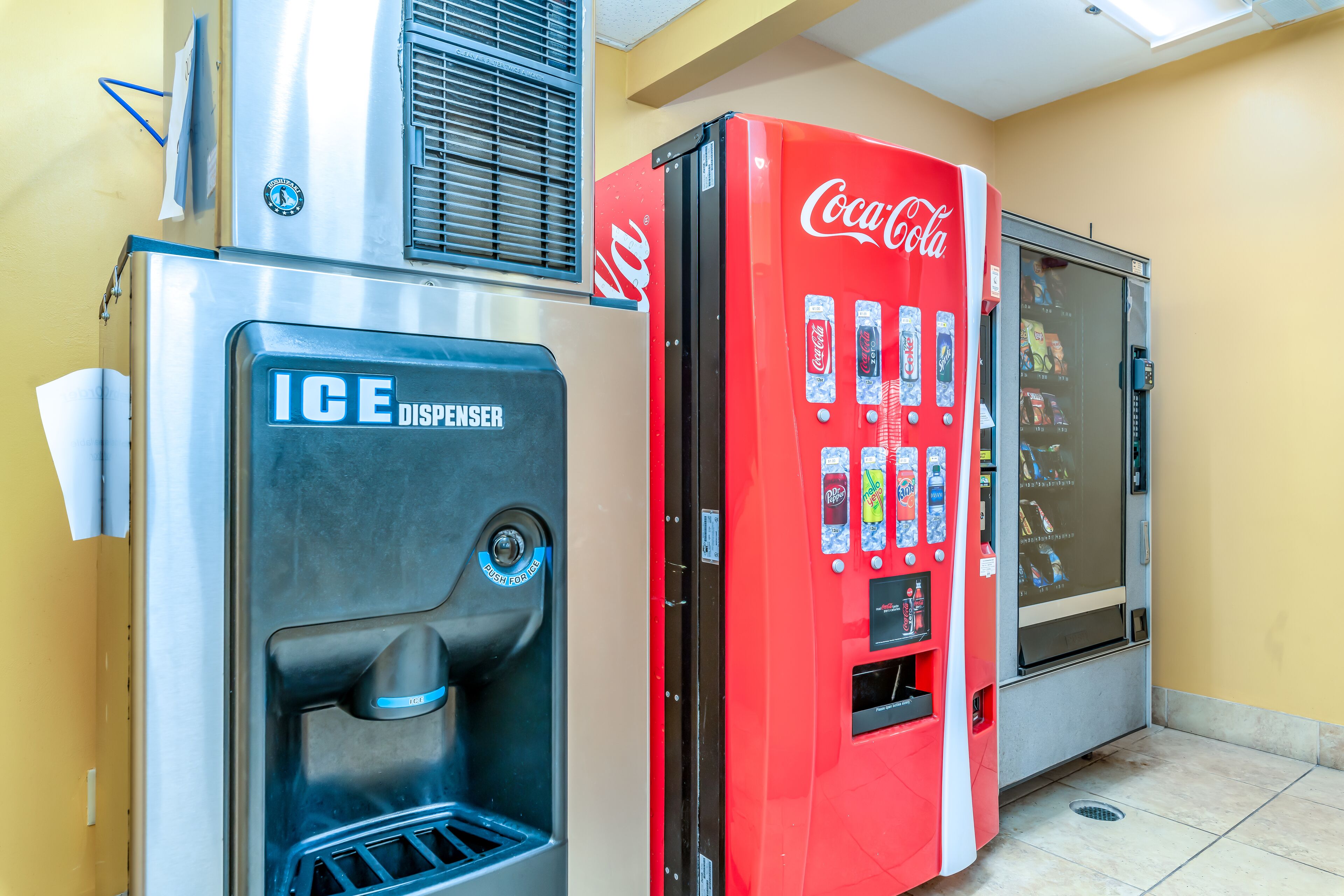 Zona de máquinas expendedoras con dispensador de hielo y máquina expendedora de Coca-Cola.