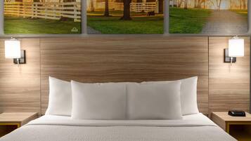 A neatly made bed with white bedding, a wooden headboard, and two bedside tables with lamps.