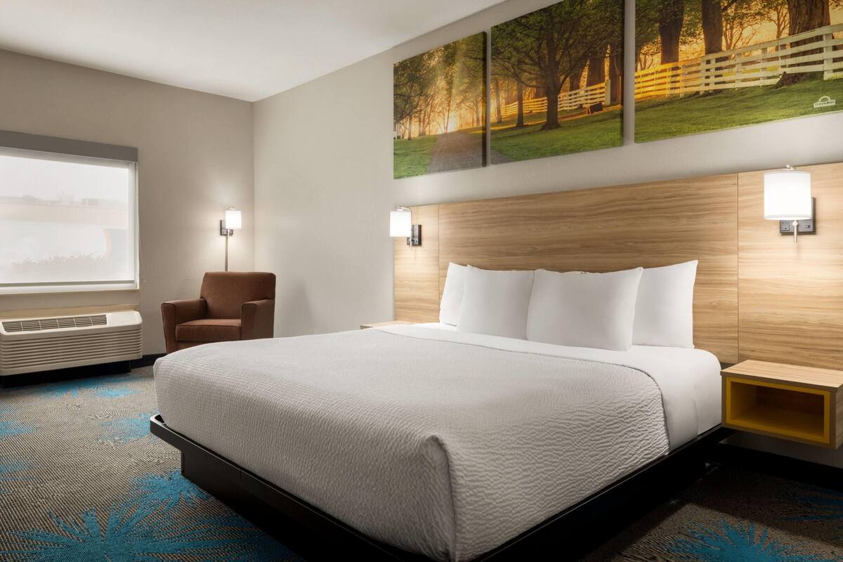 Habitación de hotel con una cama grande, una silla, un escritorio y una ventana.