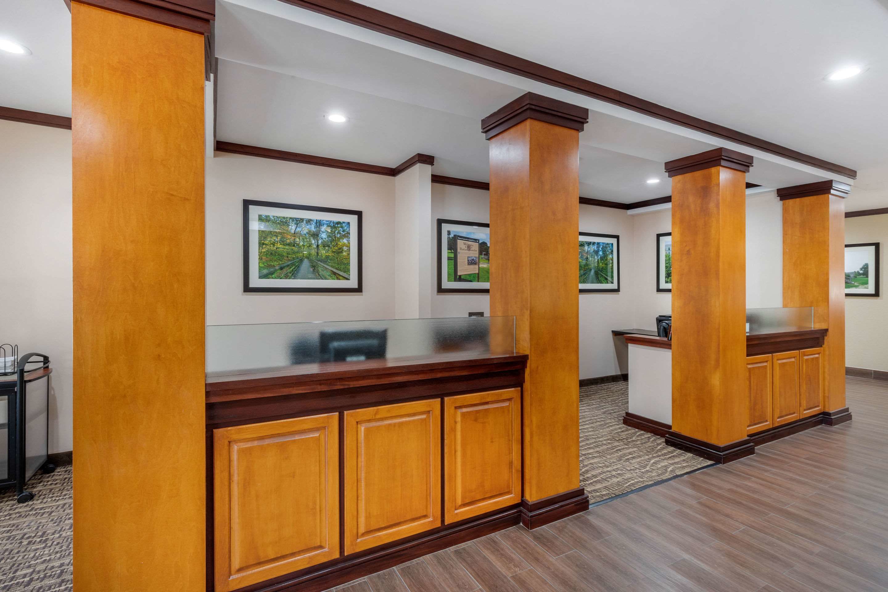 A reception area with wooden reception desks, framed pictures on the walls, and a carpeted floor.