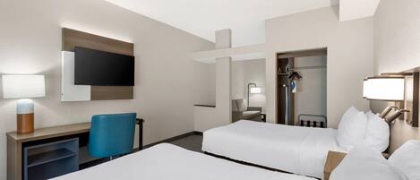 Une chambre d’hôtel avec deux lits, un bureau, une chaise, une télévision et une armoire.