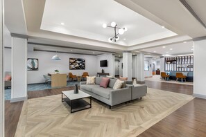 A spacious living area with a sofa, coffee table, and a TV mounted on the wall.