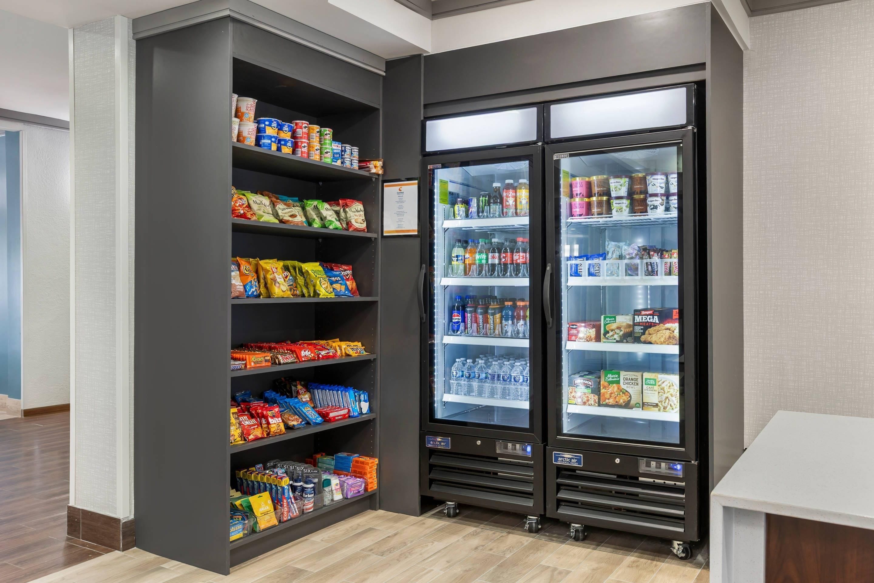 A self-service snack and beverage kiosk with shelves stocked with various snacks and a refrigerated section with drinks.