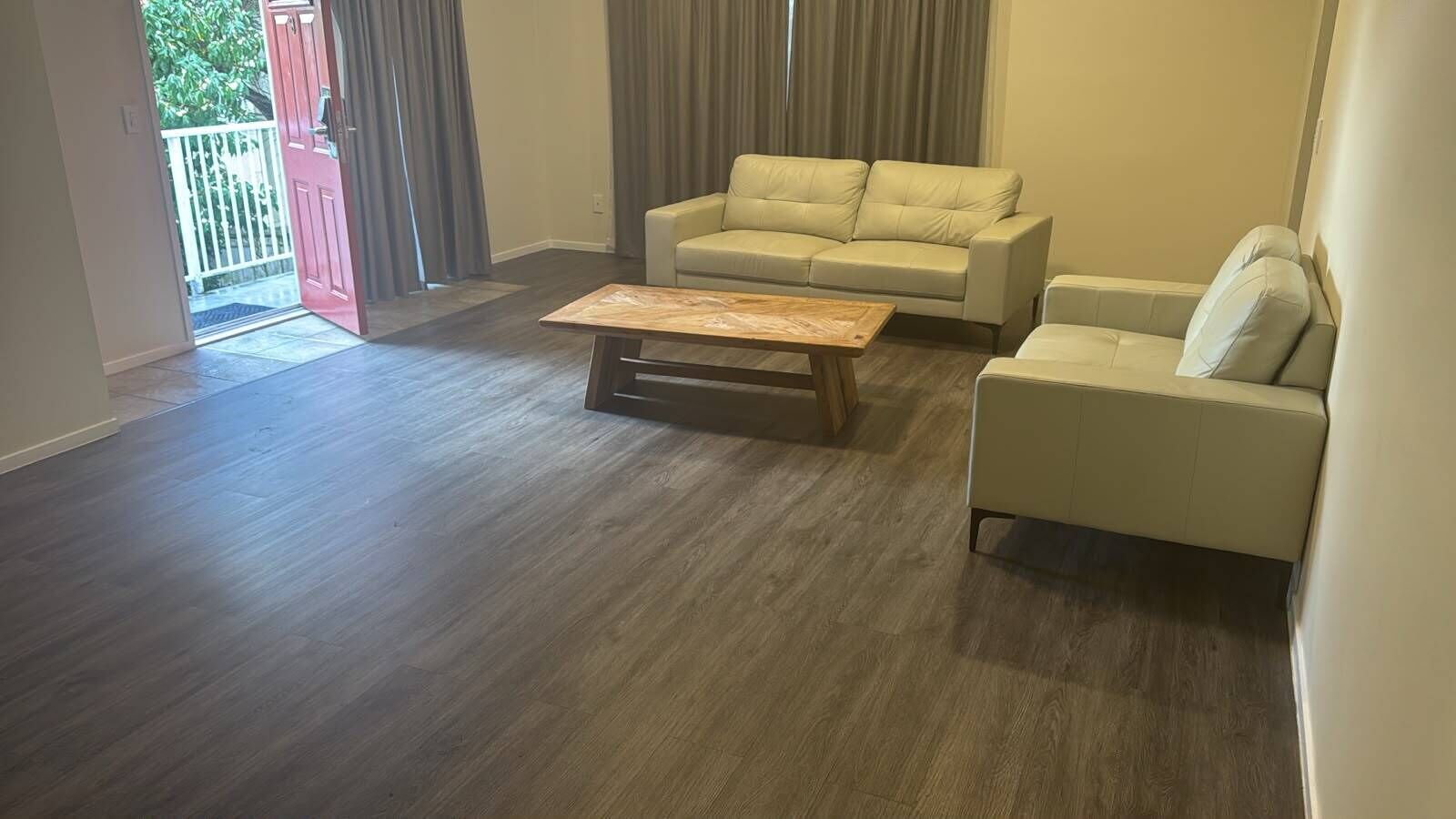 A living room with a wooden coffee table, two sofas, and a sliding glass door leading to a balcony.