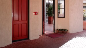A red door with a reception sign above it, a fire alarm, and a potted plant outside. - Anglesea Motel and Conference Centre (Hamilton)
