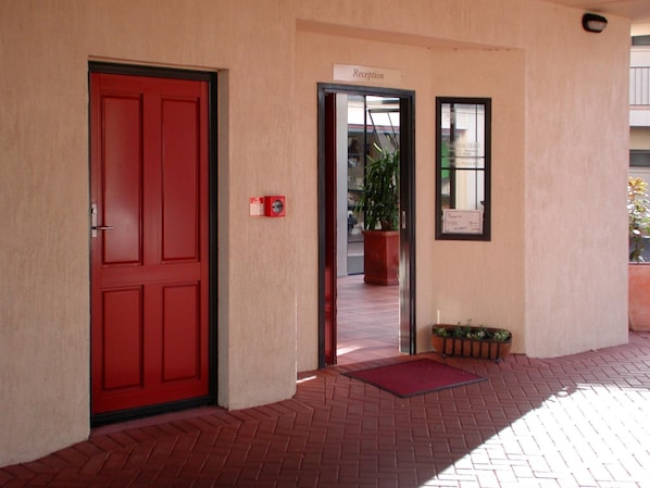 A red door with a reception sign above it, a fire alarm, and a potted plant outside. - Anglesea Motel and Conference Centre (Hamilton)