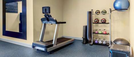A fitness room with a treadmill, exercise balls, and kettlebells.