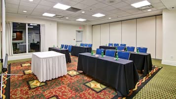 A conference room with tables, chairs, and a patterned carpet.