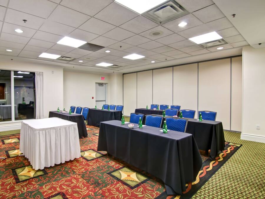 A conference room with tables, chairs, and a patterned carpet.