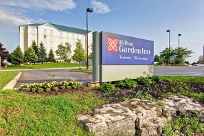 A Hilton Garden Inn sign with a building in the background. - Hilton Garden Inn Toronto - Mississauga (Mississauga)