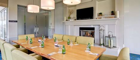 A conference room with a long table, chairs, and a fireplace.