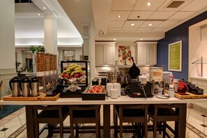 A breakfast bar with coffee makers, fruit, and waffle batter. - Hilton Garden Inn Toronto - Mississauga (Mississauga)