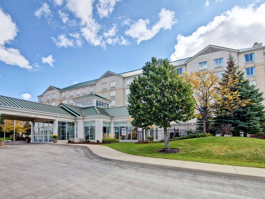 A hotel with a covered entrance, multiple floors, and a well-maintained lawn.