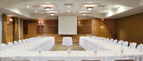 A conference room with a long table, chairs, and a projector screen.