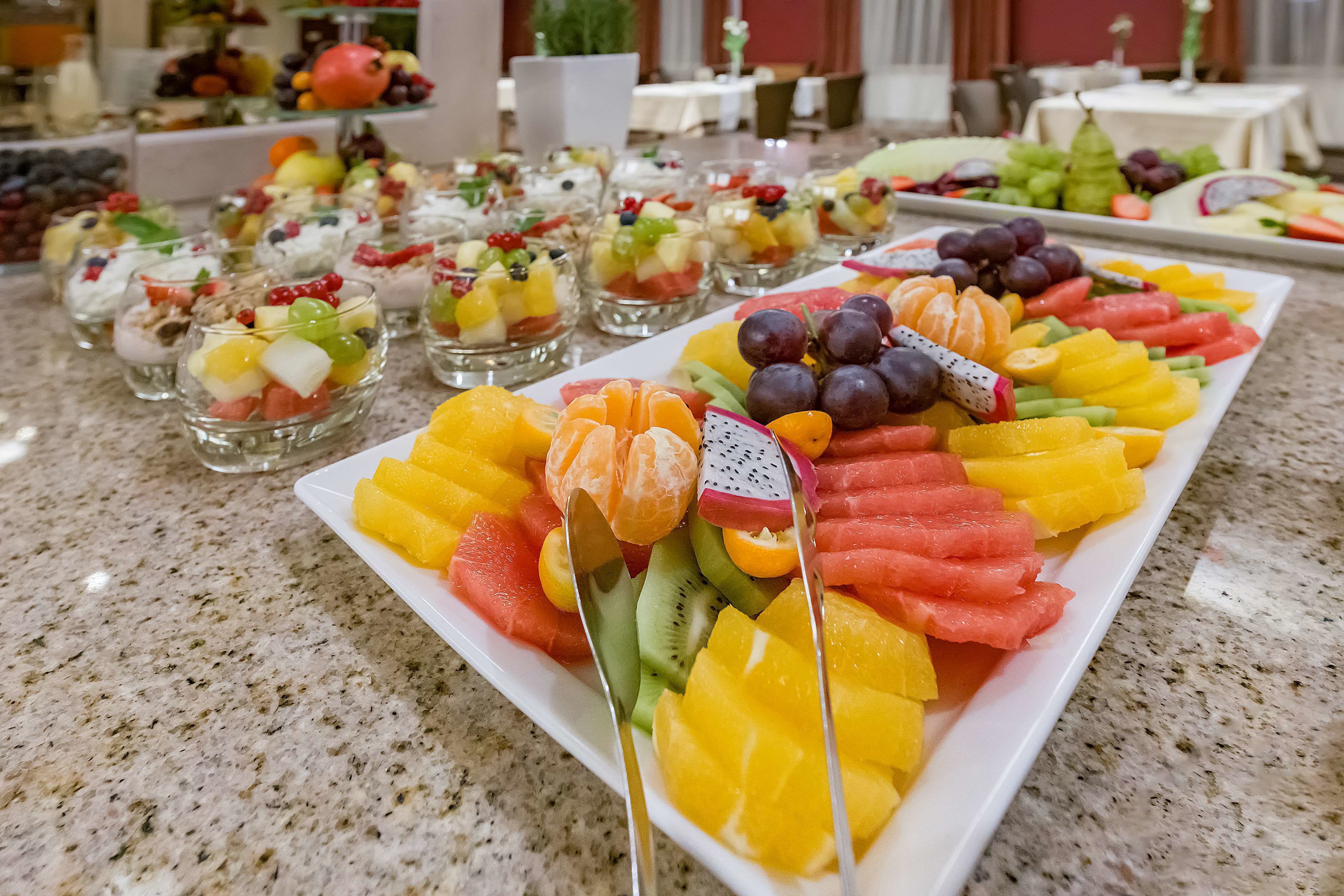 Un buffet con assortiti piatti di frutta e piccole ciotole di insalata di frutta.