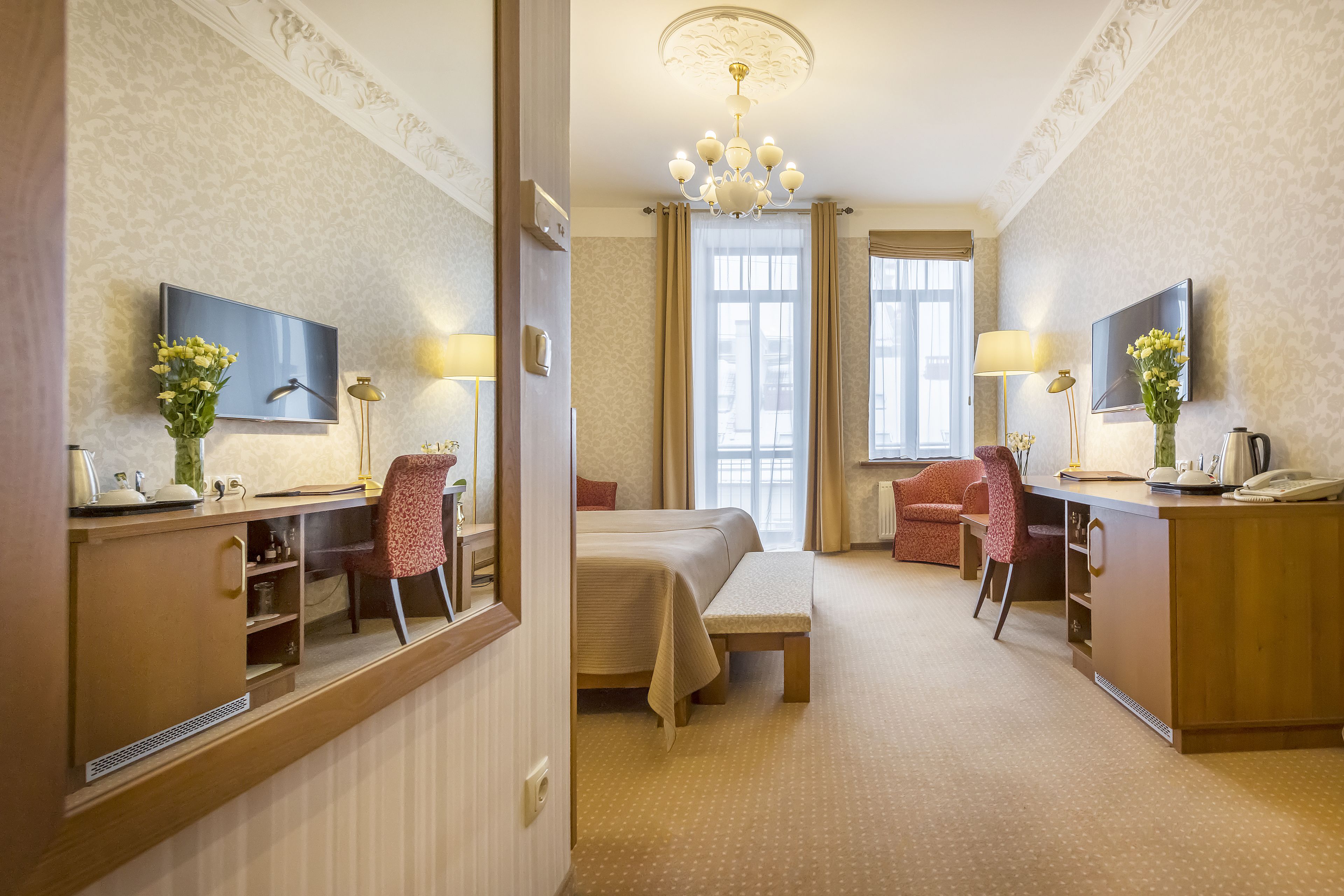 A hotel room with a bed, desk, chair, and a large window.
