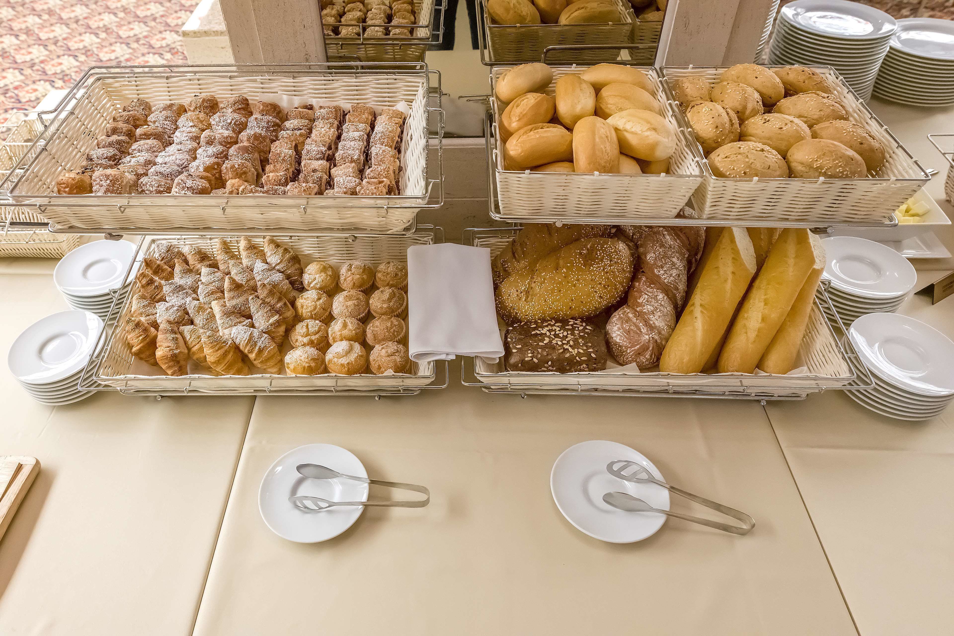 A buffet table with various baked goods and plates.