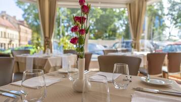 A dining table set for a meal with a vase of flowers, clear glassware, and neatly arranged tableware.