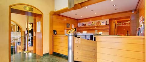 Un espace d’accueil comprenant un comptoir en bois, une vitrine et un pilier en métal.