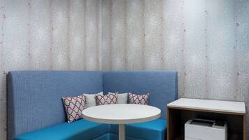 A corner seating area with a blue sofa, patterned pillows, and a small white table.