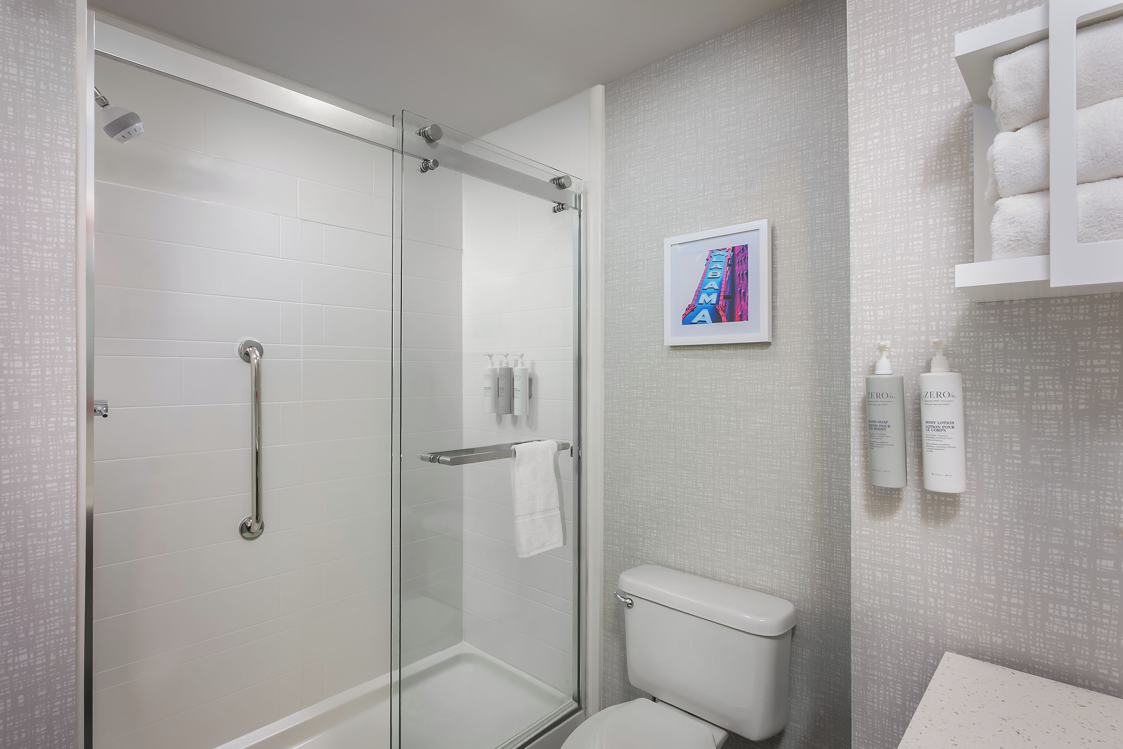 A modern bathroom with a glass-enclosed shower, a toilet, and a sink area.