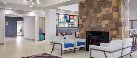 A spacious living area with a fireplace, comfortable seating, and a colorful abstract art piece on the wall.