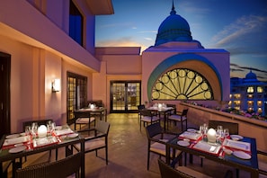 Guests can dine in style with elegant table settings and comfortable wicker chairs.