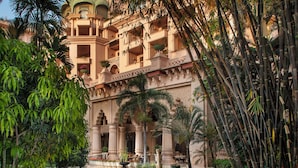 A grand building with a dome, surrounded by lush greenery and a winding pathway.