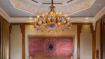 Comedor formal con una gran lámpara de araña, techo ornamentado y un llamativo adorno de pared.