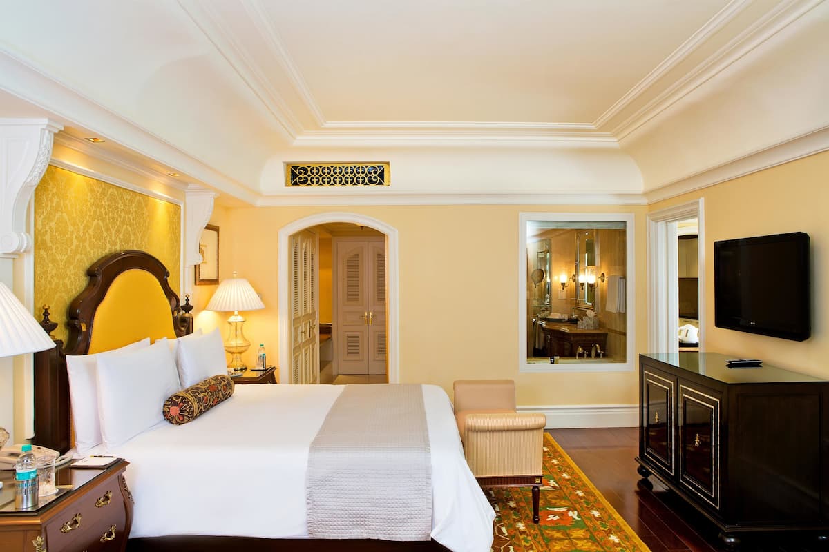 Habitación de hotel con una cama grande, televisión, armario y espejo.