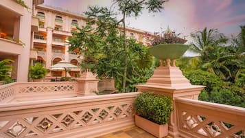A hotel courtyard with a central water feature, surrounded by lush greenery and a multi-story building with balconies.