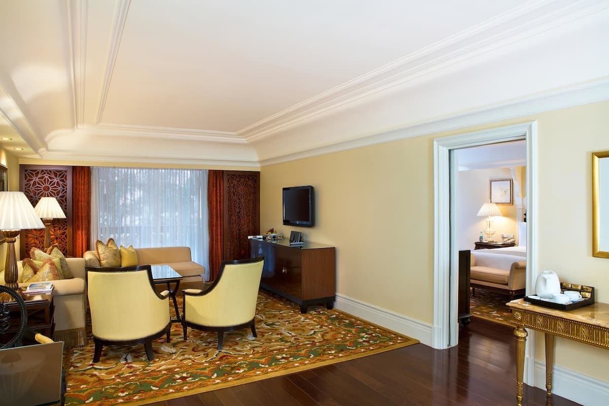 Habitación de hotel con sofá, sillas, televisor, escritorio y cama.